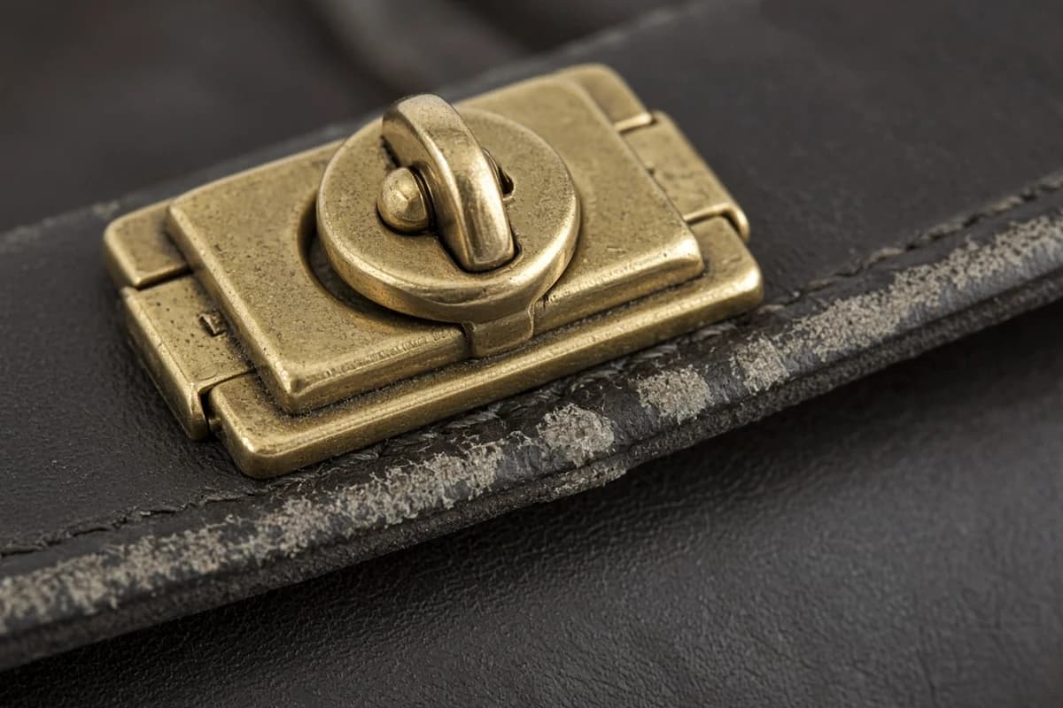 Macro close-up of handbag clasp hardware and worn flap edge for bag restoration photo quote Dubai assessment