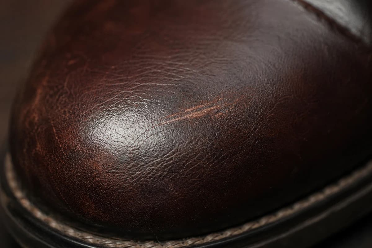 Close-up of leather grain and toe scuff before repair in Dubai