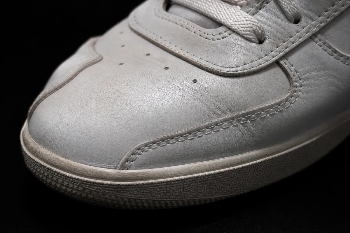 Close-up of leather sneaker toe crease showing dust and light scuff for stain assessment