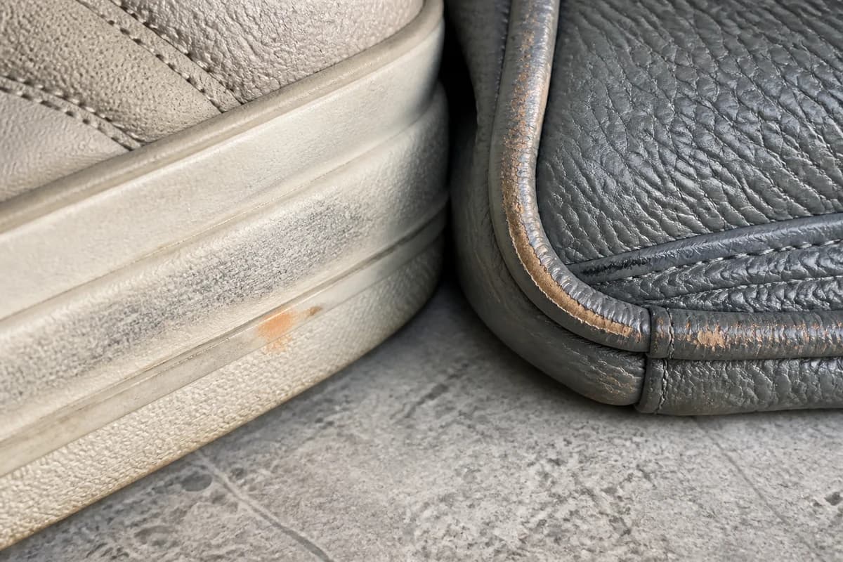Close-up of a stained sneaker midsole beside a worn leather bag corner for a Dubai care consultation