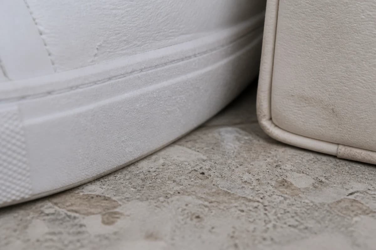 Close-up of salt haze on a white sneaker midsole beside a cream bag base after Palm promenade wear